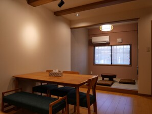 A dining area with a wooden table and chairs, a small round table, and a bench. - Kanamori - Perfect mix of east and west (Takayama)