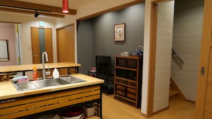 A compact kitchen with a sink, wooden countertop, and a small dining area.