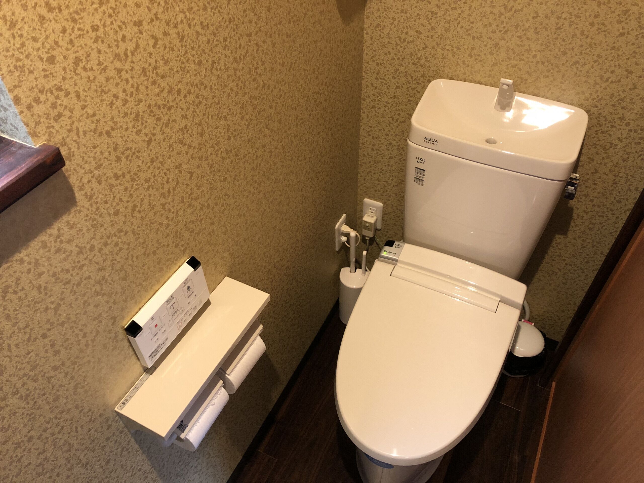 A small bathroom with a white toilet, a white sink, and a toilet paper holder.
