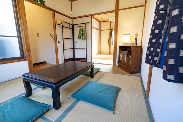 A tatami mat room with a low table, cushions, a wooden cabinet, and a sliding door.