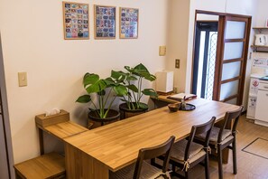 A wooden dining table with chairs, potted plants, a tissue box, and framed pictures on the wall.