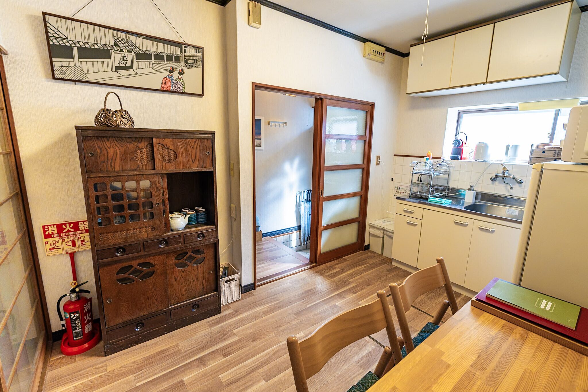 A traditional Japanese-style kitchen with wooden cabinets, a dining table with chairs, and a sliding door leading to another room.
