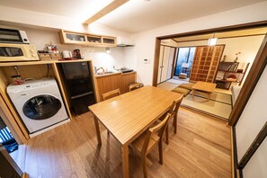 A compact kitchen with a washing machine, a refrigerator, and a dining area with a table and chairs.