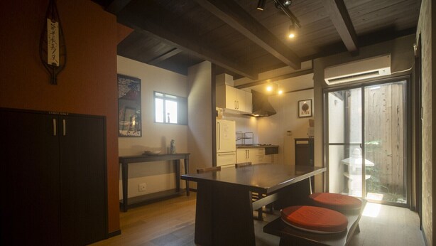 Cozinha moderna com ilha central, banquetas e vista para o exterior através de uma porta de vidro.
