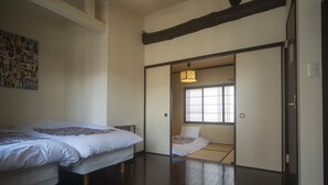 Um quarto japonês tradicional, com piso de tatame, porta deslizante que dá para um cômodo menor com futon e porta de tela shoji.