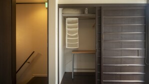 Quarto de hotel com porta deslizante para um armário, uma cama e um pequeno espaço de estar.