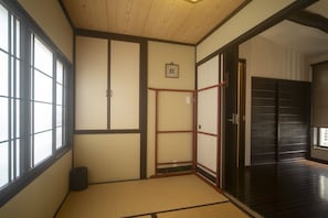 Une pièce de style japonais traditionnel, avec un sol recouvert de tatamis, des portes coulissantes et un parquet en bois foncé.