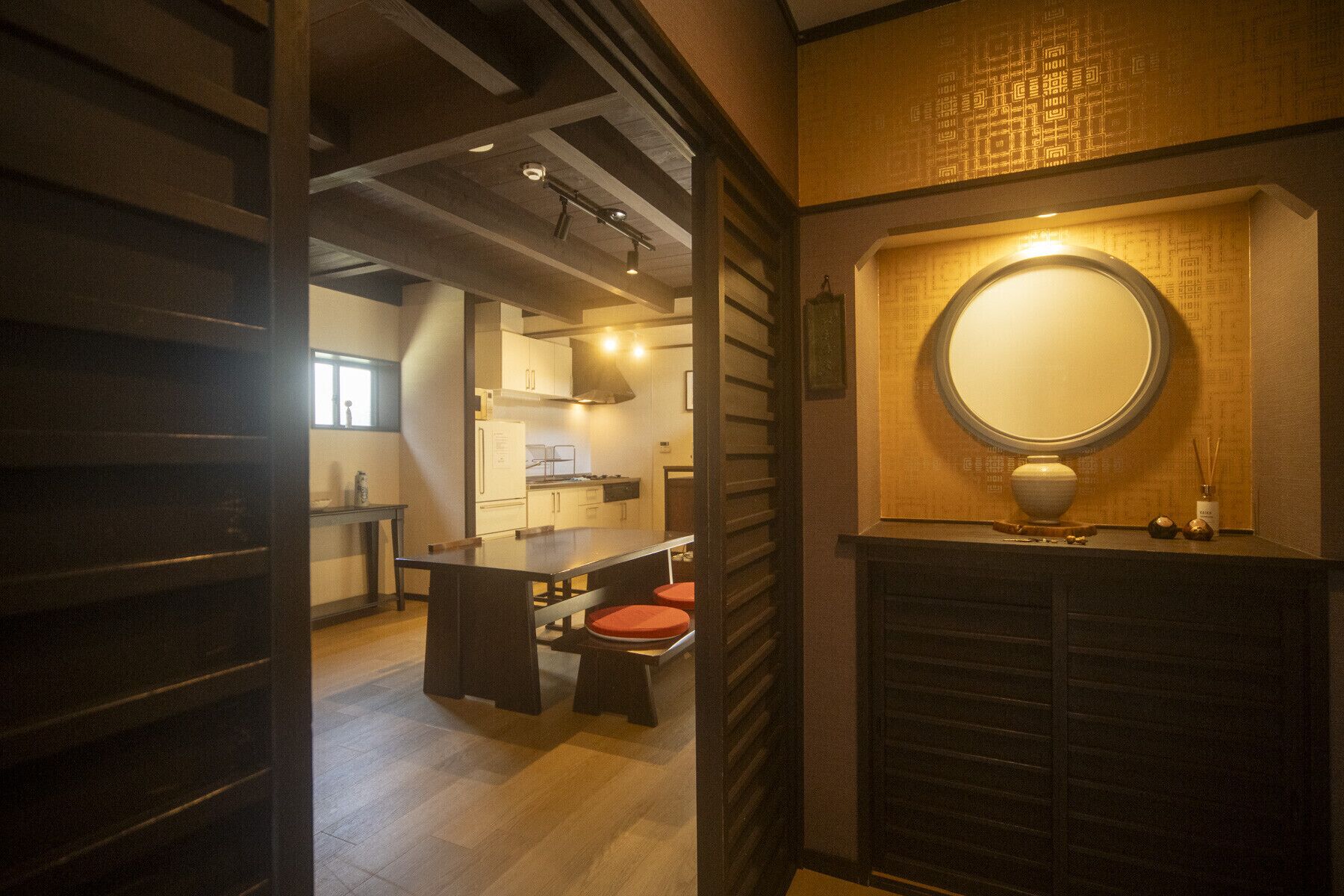 A modern interior with a dining area, a kitchen, and a bathroom with a round mirror.