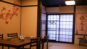 A traditional Japanese room with tatami flooring, a low table with a tea set, and a shoji screen door.