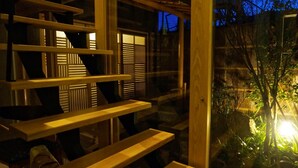 Una escalera de madera que lleva a un balcón con vistas a un jardín al anochecer.