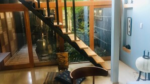 Un interior moderno con una escalera de madera, un vidrio que da al exterior y vistas a zonas verdes.