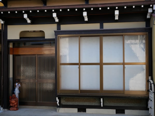Un edificio japonés tradicional con una puerta corredera y un ventanal grande.