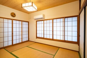 A traditional Japanese room with tatami flooring, sliding shoji doors, and a ceiling fan.
