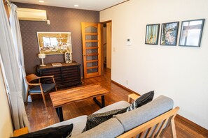 A living room with a sofa, a wooden table, a chair, a cabinet, and a painting on the wall. - Ikebukuro - Large comfortable house in Tokyo (Tokyo)