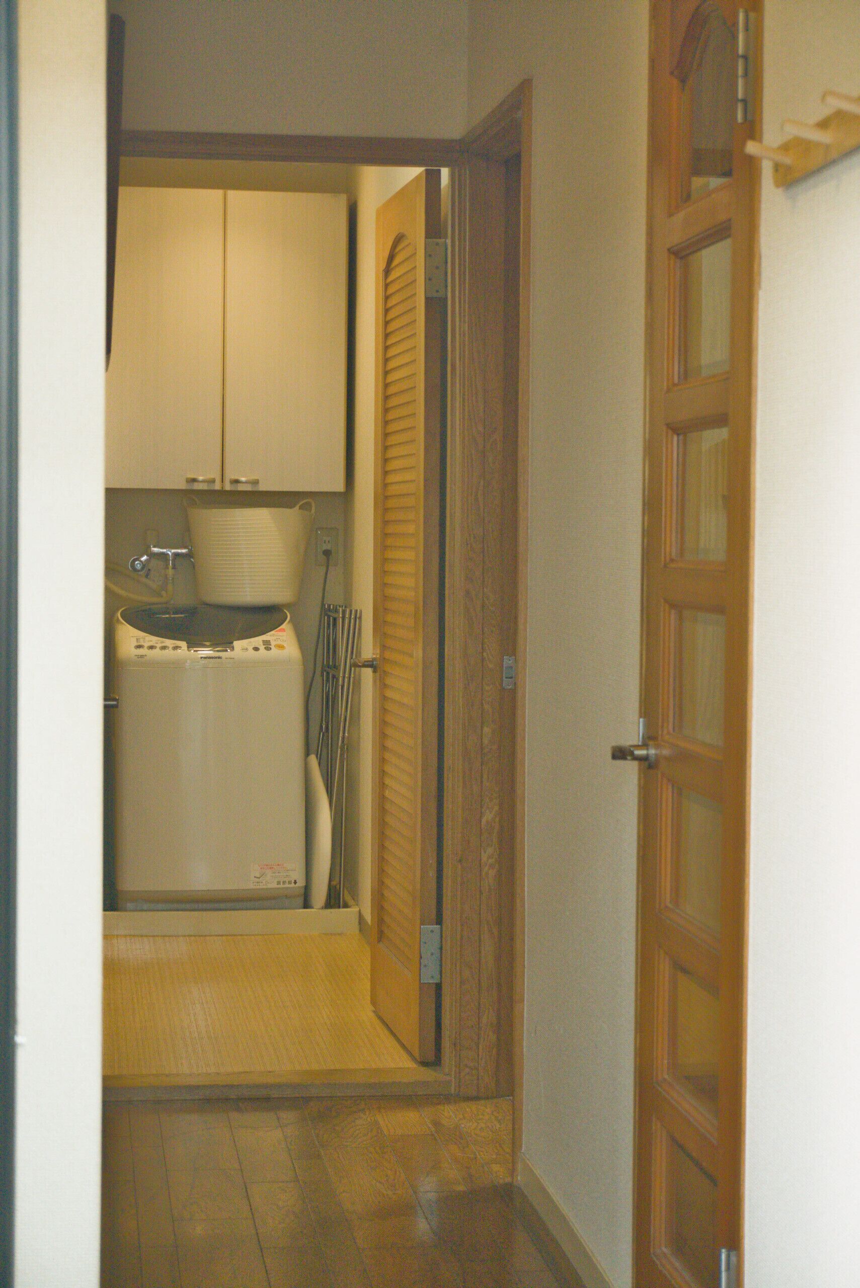 A narrow hallway leading to a laundry area with a washing machine and a drying rack.