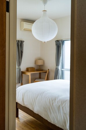 A bedroom with a bed, a desk, and a chair. There is a hanging light fixture above the bed. - Ikebukuro - Large comfortable house in Tokyo (Tokyo)
