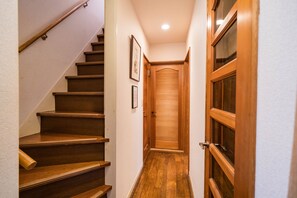 A wooden staircase leading to a door with a window, a framed picture on the wall, and a light fixture on the ceiling.