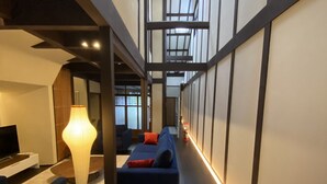 A modern interior with a long hallway, a sofa, a lamp, and a TV.