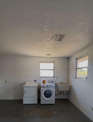 A laundry room with a washing machine, dryer, and a window.