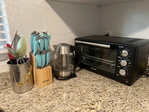 A kitchen with a toaster oven, a coffee maker, and a utensil holder on a granite countertop.