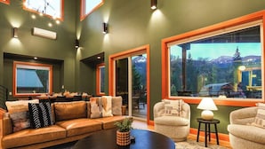 A living room with a leather sofa, a round coffee table, and a large window with a mountain view.