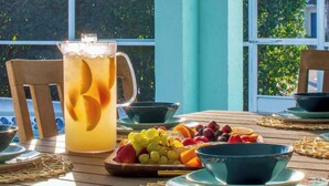 A wooden table with a pitcher of iced tea, fruit, and bowls.