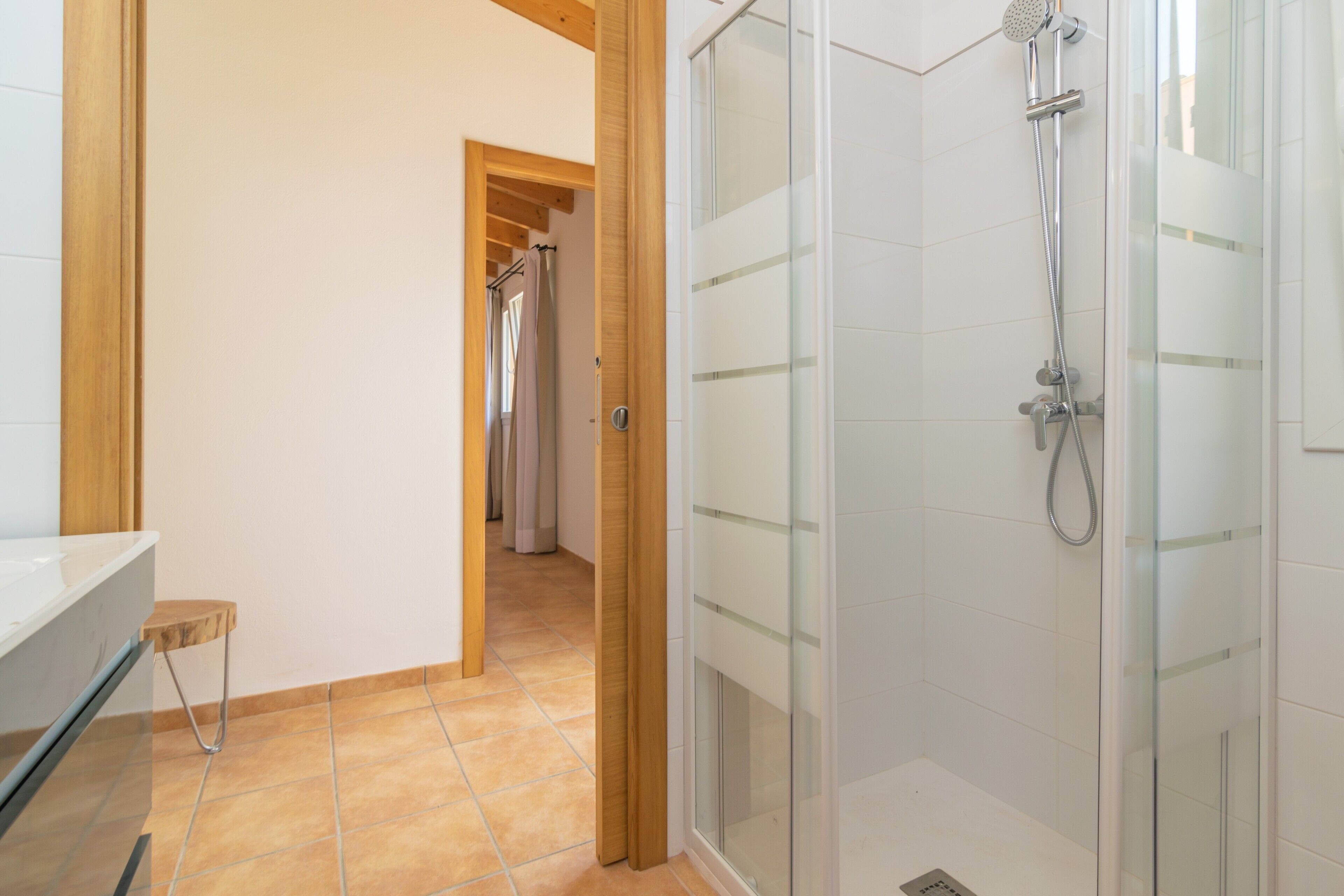 Une salle de bain avec une douche, un lavabo et un petit tabouret.