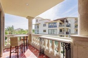A balcony with a view of a multi-story building, wicker chairs, and a tiled floor. - Condo B305 - 2 Bdrm Luxury Condo with Ocean Views (Cabo San Lucas)
