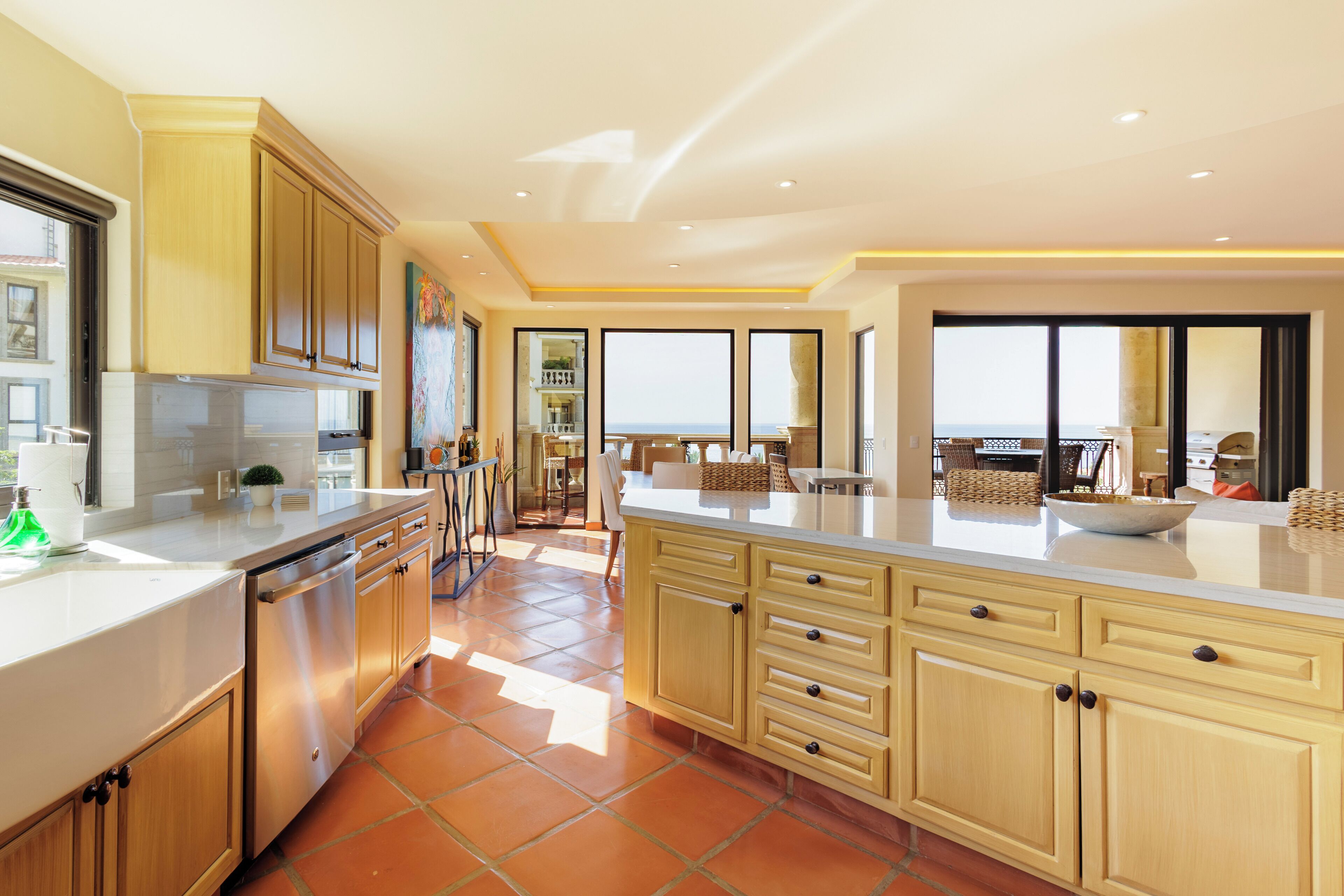 A modern kitchen with a large island, built-in appliances, and a view to the outside.