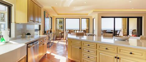 Una cocina moderna con una isla grande, electrodomésticos integrados y vistas al exterior.