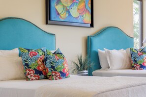 A double bed with floral-patterned pillows and a plain white bedspread. - Condo B305 - 2 Bdrm Luxury Condo with Ocean Views (Cabo San Lucas)