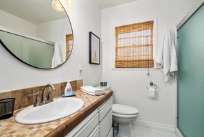 A bathroom with a white sink, a mirror, a toilet, and a window with a bamboo blind. - Peaceful, AC, WiFi, FPit, BBQ, Mile2DwnTwn, DogsOk (Paso Robles)