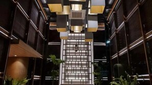 A modern interior with a central staircase, dark wooden paneling, and recessed lighting. - The Day Residence (Jakarta)