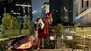 A rooftop terrace with a modern metal sculpture, outdoor seating, and a cityscape view in the background. - The Day Residence (Jakarta)