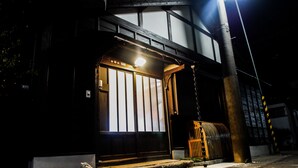A traditional Japanese building with a wooden exterior, a large sliding door, and a small porch area.