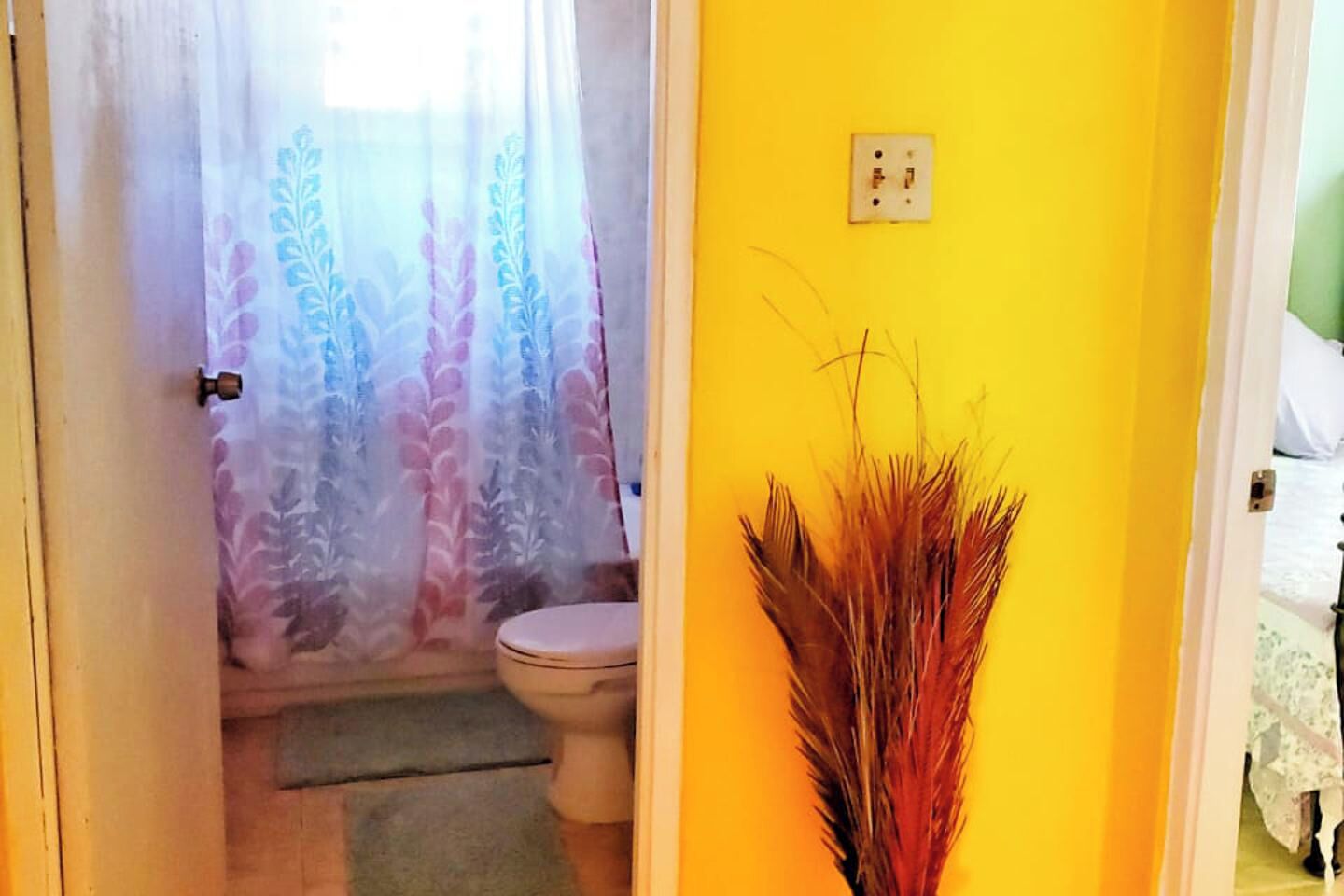 Een badkamer met toilet, douchegordijn en een gele wand.