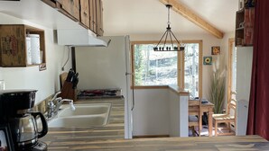 Una cucina con mobili in legno, una macchina da caffè e una finestra vista alberi.