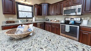 Una cucina con ripiani in granito, elettrodomestici in acciaio inossidabile e mobili in legno scuro.