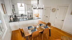 A modern kitchen with white cabinets, a black countertop, and a wooden dining table set for four. - Hot Tub;Mountain Views;steps from Arkansas River South Main (Buena Vista)