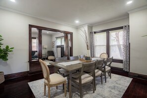 A dining area with a wooden table, six chairs, a vase with branches, and a large mirror on the wall. - 6 Bed 2.5 Bath Next to UD  Sleeps 14 PATIO (Dayton)