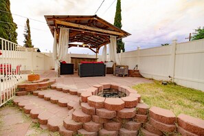 A covered patio with a fire pit, outdoor seating, and a white fence. - The Oasis- House with pool/ 2 master suites/ fire pit/ outdoor bar (Tucson)