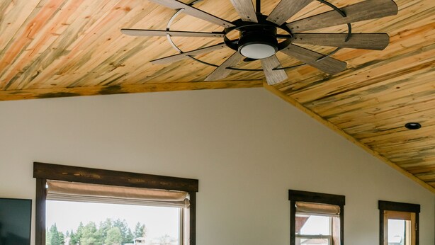 A living room with a ceiling fan, a large window, and a door. - Relaxing, quiet cabin close to Glacier Park! (Columbia Falls)