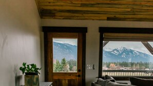 A room with a wooden door leading to a balcony with a mountain view. - Relaxing, quiet cabin close to Glacier Park! (Columbia Falls)