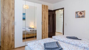 Une chambre à coucher avec un lit, une armoire, un miroir et un tableau accroché au mur.