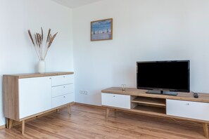A modern living room with a TV, wooden furniture, and a painting on the wall.