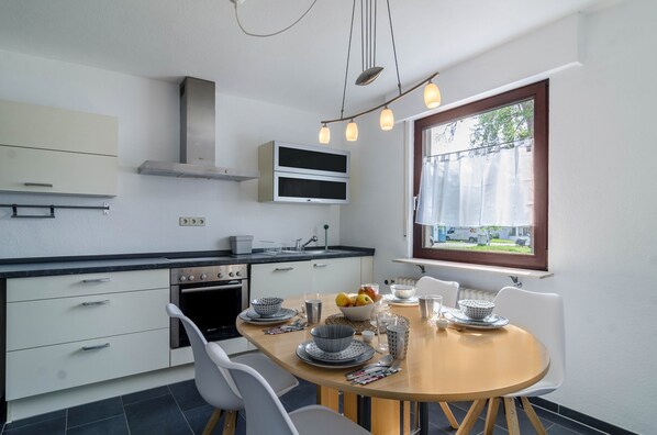 A modern kitchen with a dining area, built-in oven, microwave, and a window with a view.