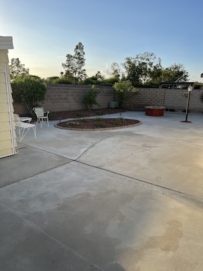 A concrete patio with a brick wall, a small garden area, and outdoor furniture.