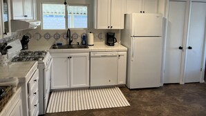 A compact kitchen with white cabinets, a gas stove, a dishwasher, and a refrigerator.