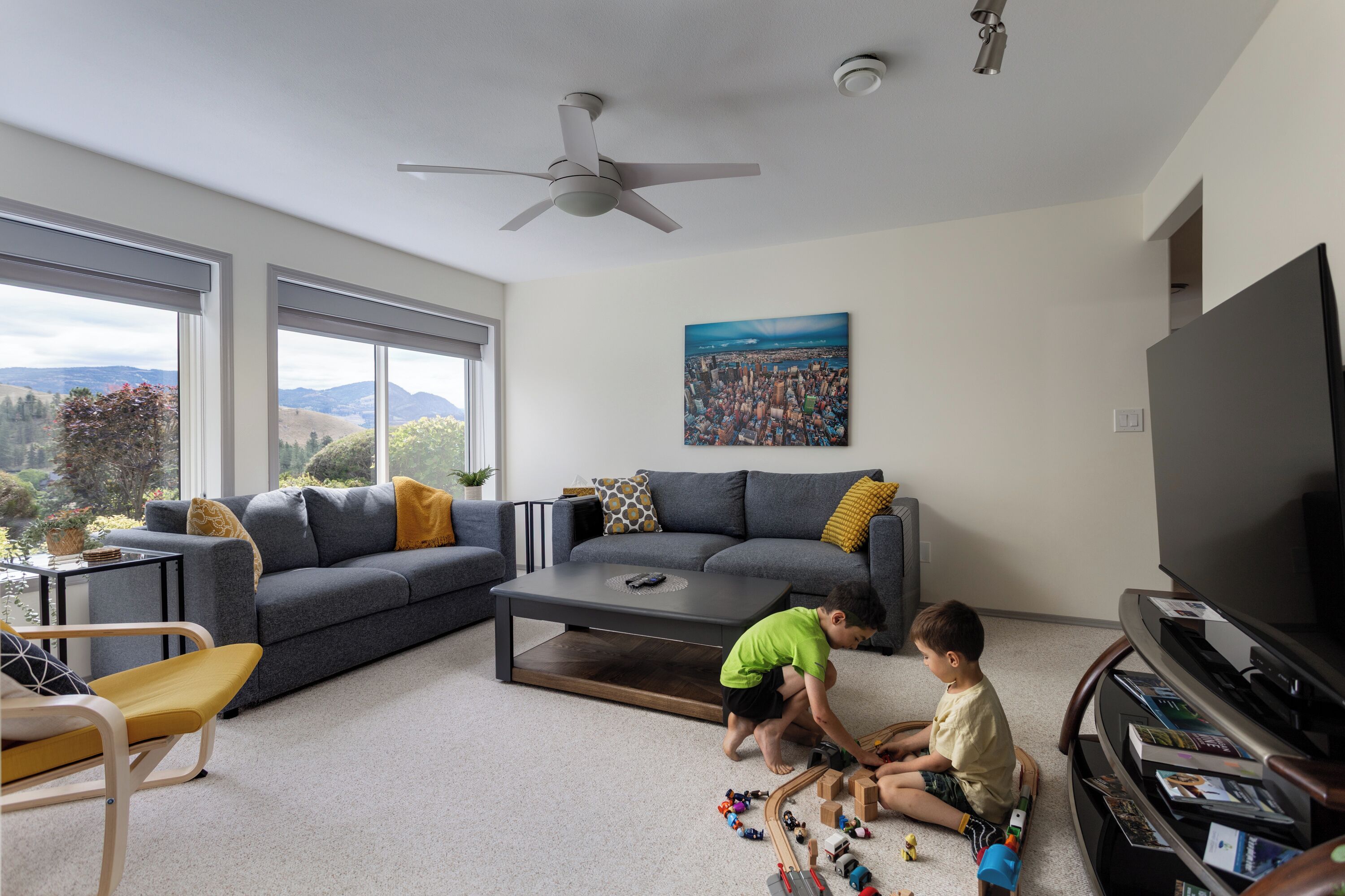 A living room with a sofa, coffee table, television, and children playing with toys.