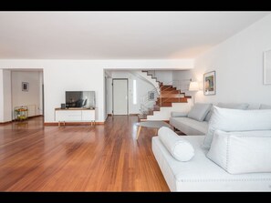 Relax in this stylish living space with a sofa, flat-screen TV, and staircase leading to an upper level.